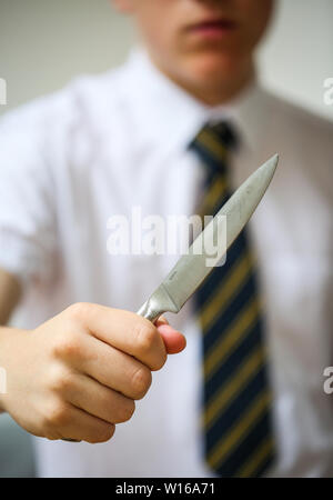 Teenage school boy holding a knife Couteau pour illustrer la criminalité dans les écoles britanniques Banque D'Images