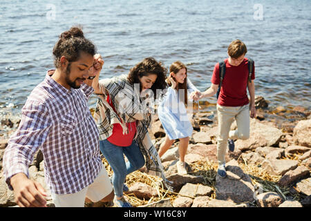 High angle portrait de deux jeunes couples walking on Rocky beach par mer, copy space Banque D'Images