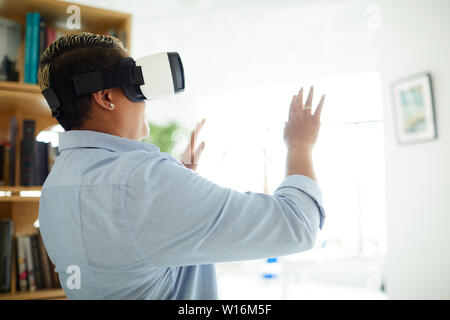 Vue arrière de manly black woman in casual shirt faire arrêter tout en utilisant des gestes de l'appareil de réalité virtuelle Banque D'Images