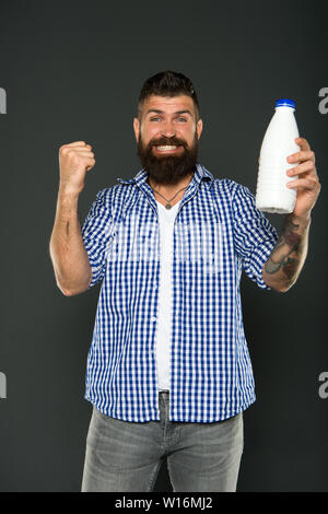 Les produits laitiers sont de bonnes sources de protéines et de calcium. Homme barbu tenant une bouteille de boisson laitière sur fond gris. Régime alimentaire des produits laitiers bénéficiant d'hipster heureux. Menu des produits laitiers. Banque D'Images