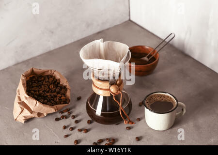 Café savoureux dans la tasse et chemex sur table gris Banque D'Images