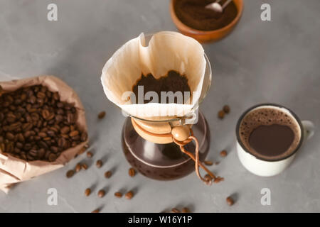 Café savoureux dans la tasse et chemex sur table gris Banque D'Images