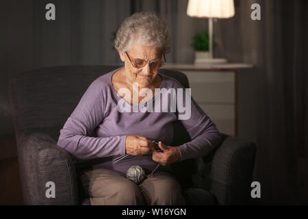Senior woman knitting à la maison en fin de soirée Banque D'Images