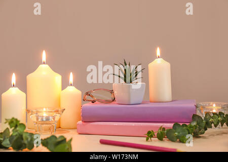 Beau brûler des bougies, livres et décor floral sur table Banque D'Images