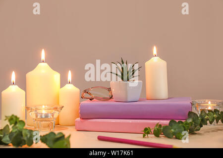 Beau brûler des bougies, livres et décor floral sur table Banque D'Images