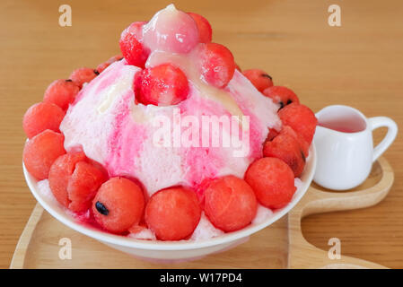 Dessert sucré Bingsu korea style rasé bingsoo / pastèque fruits sur glace topping avec du lait et du sirop de fruits dans le bac sur la table en bois Banque D'Images