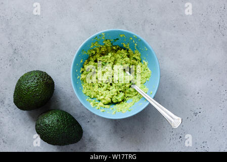 La purée d'avocat dans un bol sur fond de béton gris. Vue de dessus de table. La cuisine végétarienne ou végétalienne saine sauce ou trempette Banque D'Images