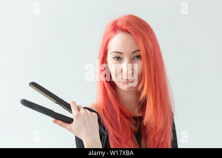 Salon de beauté, coiffure et personnes concept - jeune femme avec des cheveux colorés holding fer à friser sur fond blanc Banque D'Images