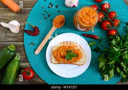 Délicieux caviar squash dans un bocal et la propagation sur les tranches de pain blanc sur la table. Le caviar fait maison avec les courgettes, l'ail, carottes, sauce tomate. Vegan Banque D'Images