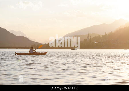 Femme kayak au coucher du soleil dans le lac Weissensee, Autriche Banque D'Images
