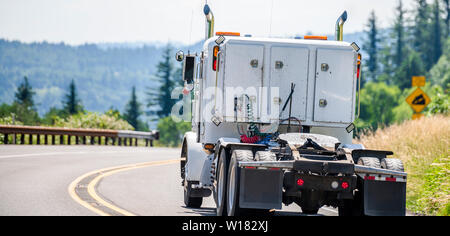 Gros camion blanc de qualité industrielle populaire puissant semi classique tracteur routier avec cinquième roue de l'attelage d'exécution sur la route de montagne sinueuse avec hill et g Banque D'Images
