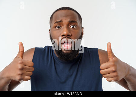 Young african american man sur fond isolé portant sport wear smiling with happy face à avec pouce vers le haut. Banque D'Images