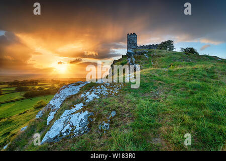 Tempête spectaculaire coucher de soleil sur la chapelle perché au sommet d'Brentor près de Tavistock sur le bord du Parc National de Dartmoor dans le Devon Banque D'Images