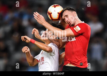 Joueur de football Selnaes Norvégien Ole, haut, de Shenzhen C.F. chefs la balle contre un joueur de Shanghai EPOP dans leur 15e match au cours de l'Association de football chinoise 2019 Super League (CSL) dans la ville de Shenzhen, province du Guangdong en Chine du sud, le 30 juin 2019. Epop Shanghai Shenzhen défait C.F. 1-0. Banque D'Images