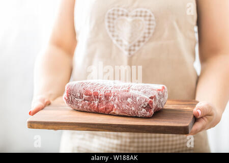 Femme cuisinière holding wooden board de matières et la viande de boeuf congelé Banque D'Images