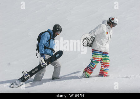 SIBIU, ROUMANIE - 13 mars 2010 : Homme snowboarder portant sa board marche dans les montagnes de Fagaras. Banque D'Images