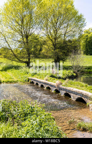 Un vieux pont de pierre à travers le ruisseau de Sherborne près du village de Cotswold, Sherborne Gloucestershire UK Banque D'Images