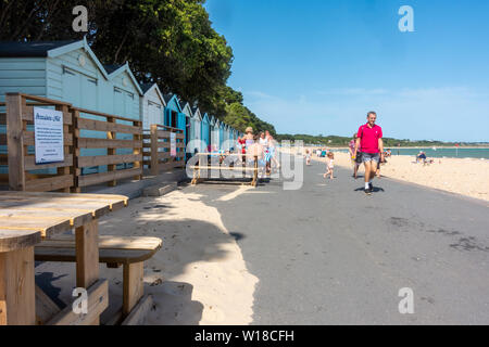 Rangée de cabines de plage dans différents tons de bleu pastel courir le long du haut de plage Avon à Mudeford Christchurch, dans le Dorset, UK. Une plage de sable avec des cailloux. Banque D'Images