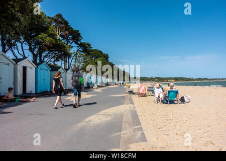 Avon Beach à Mudeford Christchurch, dans le Dorset, UK. Une plage de sable avec des cabanes de plage bordant le haut de la plage. Les gens assis dans des transats sur le sable. Banque D'Images