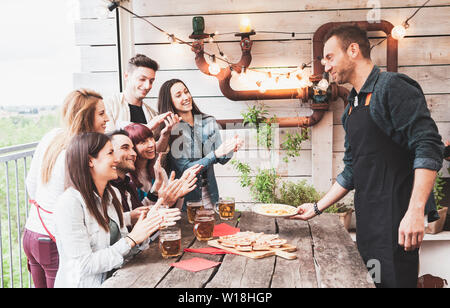 Groupe d'amis heureux de boire une bière et manger une pizza à la brasserie bar restaurant. concept avec des jeunes ayant un véritable plaisir Banque D'Images