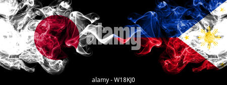 Le Japon contre les Philippines, Philippines smoky mystic drapeaux placés côte à côte. Soyeux de couleur épais fume combinaison des Philippines, Philippines et Japonais fl Banque D'Images