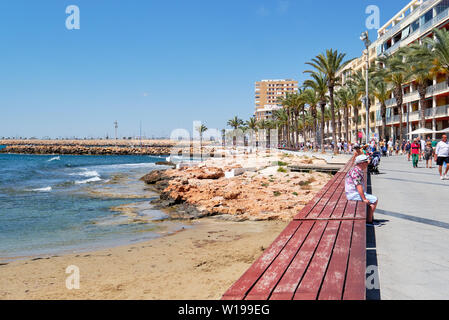 Torrevieja, Espagne - 16 mai 2019 : Les gens assis sur un banc de repos le long de la promenade de Torrevieja resort city Banque D'Images