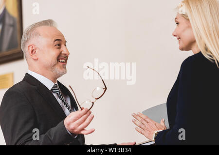 Enseignant à la recherche de beau blond woman alors que holding glasses Banque D'Images