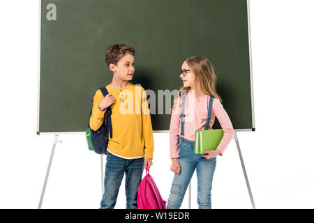 Deux écoliers avec sacs à dos et les livres debout près de blackboard isolated on white Banque D'Images