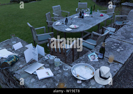 La suite des débris de verres, bouteilles et assiettes à l'aube, le matin après un 50e anniversaire, réparties autour du jardin dans le Herefordshire campagne, le 23 juin 2019, dans la région de Kington, Herefordshire, Angleterre. Banque D'Images