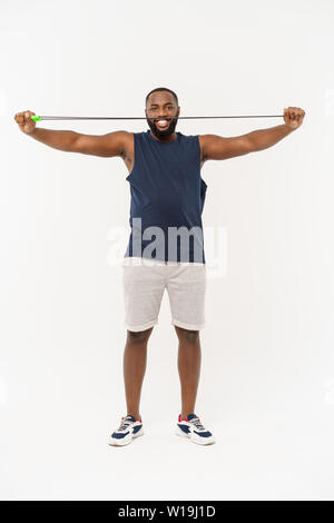 Tiré de l'homme masculin la corde à sauter. Jeune homme musclé avec l'exercice de la corde à sauter à l'arrière-plan gris Banque D'Images