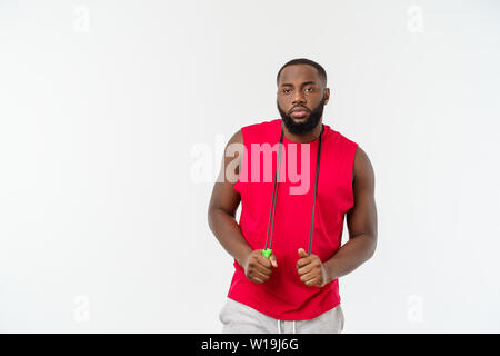 Tiré de l'homme masculin la corde à sauter. Jeune homme musclé avec l'exercice de la corde à sauter à l'arrière-plan gris Banque D'Images