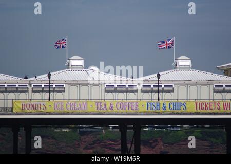 Drapeaux Union Jack's Flying sur Paignton Pier sur une sombre journée d'été à Torquay meeting aérien. Devon, Royaume-Uni. Banque D'Images