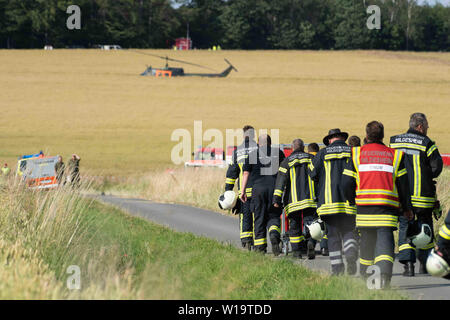 Aerzen, Allemagne. 1er juillet 2019. Les pompiers de marche le long d'un chemin à l'emplacement de l'accident d'un hélicoptère de l'armée allemande. La Bundeswehr a confirmé l'écrasement d'un hélicoptère d'entraînement en Basse-Saxe. L'Eurocopter EC 135 machine a été impliqué dans un accident d'environ 30 kilomètres à l'ouest de Hameln, un porte-parole de l'armée allemande a déclaré à la presse allemande. -L'organisme. Il y avait deux personnes à bord. L'avion appartient à l'International Helicopter Training Centre de Bückeburg. Credit : Swen Pförtner/dpa/Alamy Live News Banque D'Images