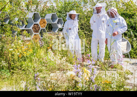 Londres, Royaume-Uni. 1er juillet 2019. Le pollinisateur urbain jardin, jardin de vie -Présenter leur ambition commune pour sauver les pollinisateurs dans tout le Royaume-Uni et mettre un terme à la diminution de leur nombre. onny, Pâques était vêtue de son plein-corps l'apiculture costume avec Warner l'apiculteurs stagiaire de RHS Wisley Garden. Il y avait aussi Warner l G&T sur le jardin à la fois pour l'équipe et tout le plaisir de ses clients. Le Festival des jardins de Hampton Court, 2019. Crédit : Guy Bell/Alamy Live News Banque D'Images