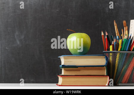 Définir pour l'étudiant. Une pile de livres, une pomme, des crayons dans le contexte de l'école tableau noir. Le concept de l'éducation. Copy space Banque D'Images