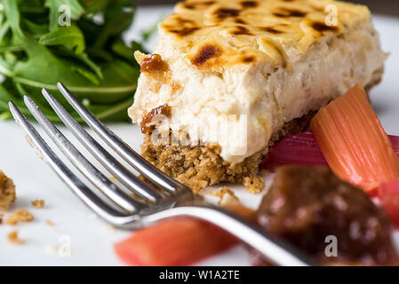 Gâteau au fromage au four salés avec de la rhubarbe marinés et chutney de rhubarbe, vue rapprochée avec la fourchette Banque D'Images