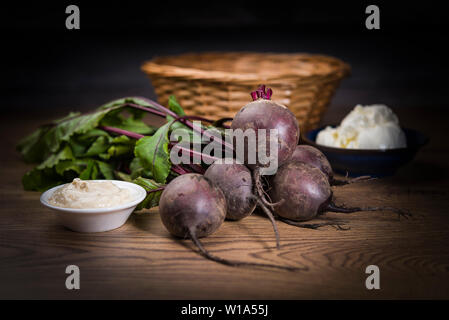Tas de matières betterave rouge sur une table en bois avec panier en osier et des bols de crème et au raifort Banque D'Images