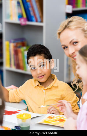 Focus sélectif de happy african american kid looking at camera près de femme et enfant Banque D'Images