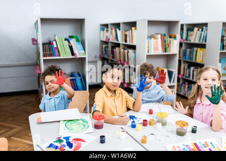 Happy kids multiculturels colorés montrant les mains avec de la peinture gouache Banque D'Images
