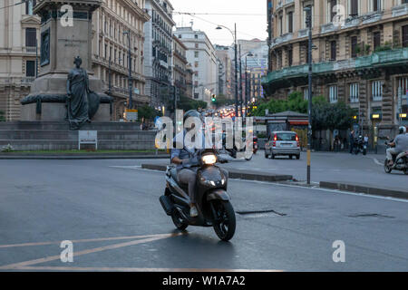 Naples, Italie - 21 juin 2019 : un homme de la trottinette dans le trafic urbain. Porter un casque de protection, obligatoires par la loi. Banque D'Images