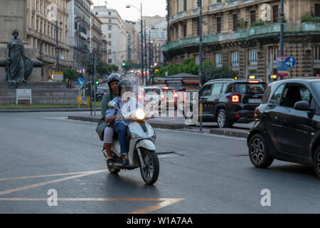 Naples, Italie - 21 juin 2019 : un couple riding a scooter dans la circulation urbaine. Les deux porter des casques de protection, obligatoires par la loi. Banque D'Images