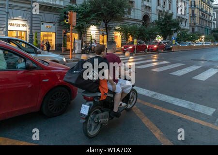 Naples, Italie - 21 juin 2019 : deux garçons de la trottinette est arrêté au feu. Aucun des deux jeunes hommes est de porter un casque de protection, qui Banque D'Images