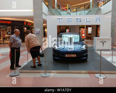 L'inspection d'un couple de personnes âgées 3 Modèle Tesla en exposition dans un centre commercial Banque D'Images