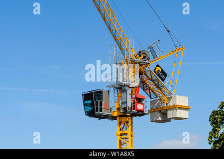 Tall Yellow Crane Tower & levage working on construction site contre ciel bleu profond (cabine, mât, flèche et poids) - York, North Yorkshire, Angleterre, Royaume-Uni. Banque D'Images