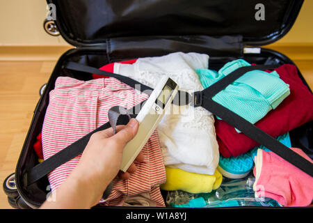 Emballage pèse-bagages numérique femme en assurance afin d'éviter les surplus de bagages dans le concept de l'aéroport. Réduire le stress de voyage. Banque D'Images