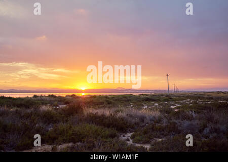 Salt Lake de Las Salinas dans la station balnéaire espagnole de Torrevieja, au coucher de soleil rougeoyant lumineux jaune derrière l'horizon des eaux. Espagne Banque D'Images
