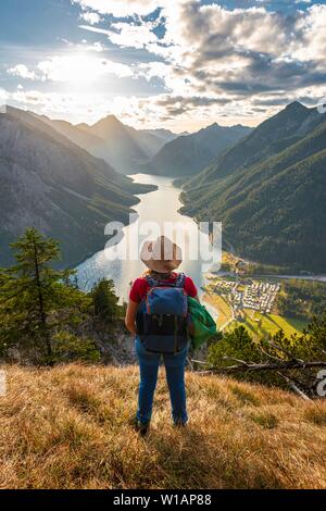 Female hiker avec un chapeau de soleil à dans la distance, le lac Plansee, Alpes Ammergau, district de Reutte, Tyrol, Autriche Banque D'Images