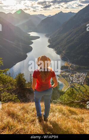 Female hiker avec un chapeau de soleil à dans la distance, le lac Plansee, Alpes Ammergau, district de Reutte, Tyrol, Autriche Banque D'Images