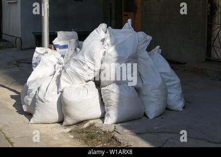 Les déchets de construction appartement après réparation. Tas de déchets de construction à proximité d'un bâtiment résidentiel à plusieurs étages. Les débris de construction dans les sacs blancs pre Banque D'Images