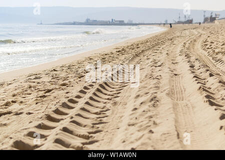 Des traces de pneus de voiture sur le sable de la mer plage au bord de l'eau. Tobogan voitures imprime sur du sable de mer humide au cours de la journée, selective focus. Banque D'Images